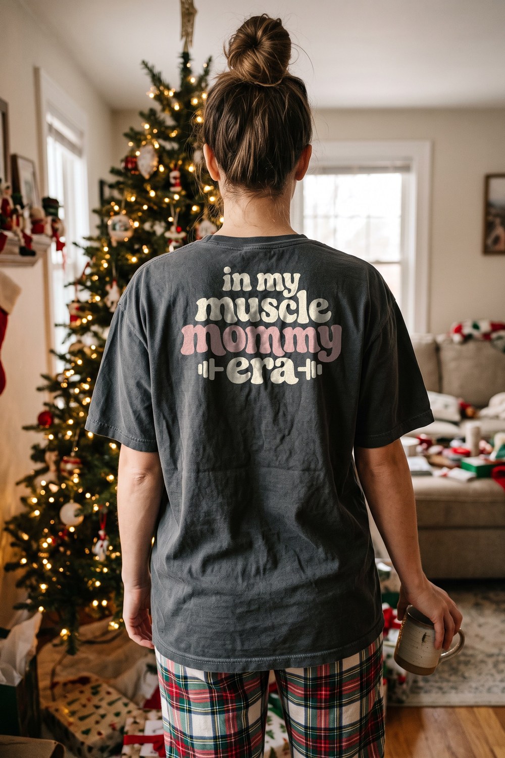 In My Muscle Mommy Era oversized tee with plaid pyjama pants by the Christmas tree